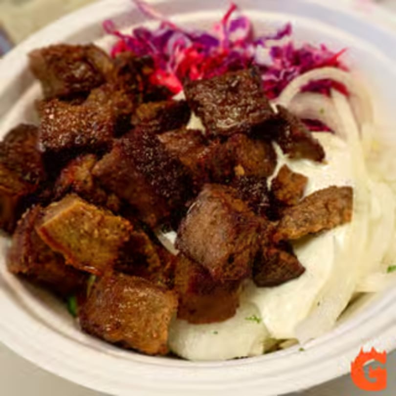 Mediterranean bowl with seasoned meat, white sauce, and red cabbage in a white bowl.